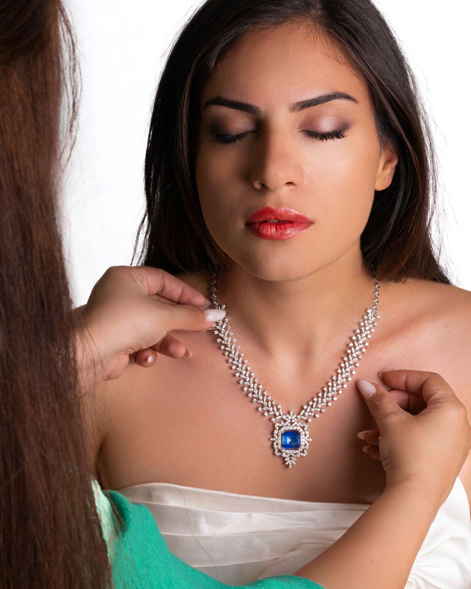 Custom-made gold and diamond necklace with blue gemstone being fitted on a model – handcrafted jewelry in Dubai.
